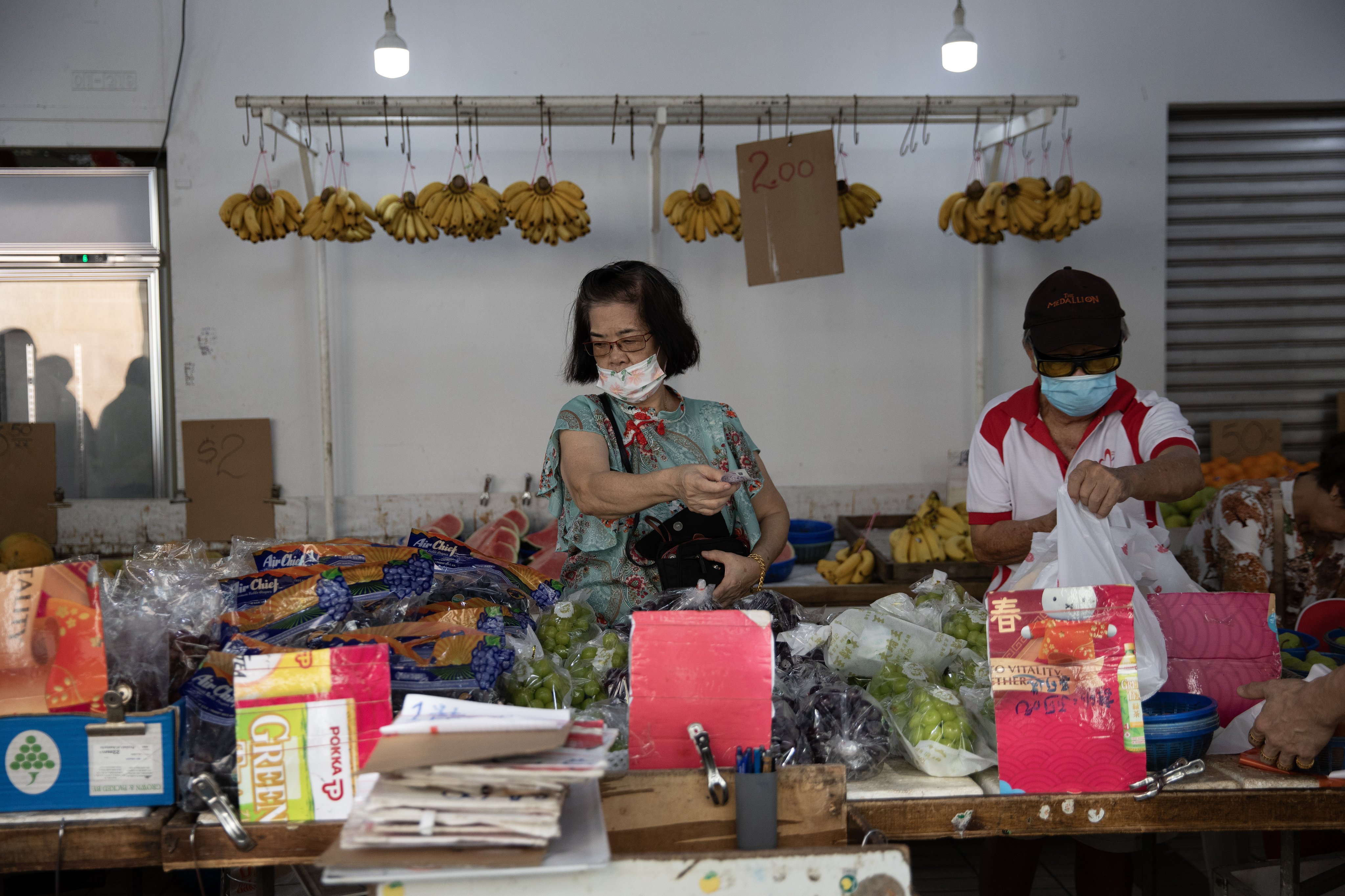 People buy fruit at a neighbourhood market in Singapore. While inflation has eased from a peak of 5.5 per cent last year, the financial burden remains significant. Photo: EPA-EFE