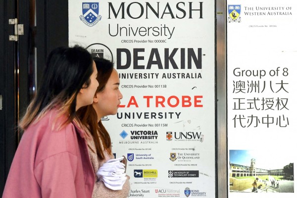 Women walk past signage advertising Australian universities in Melbourne’s central business district. Photo: AFP